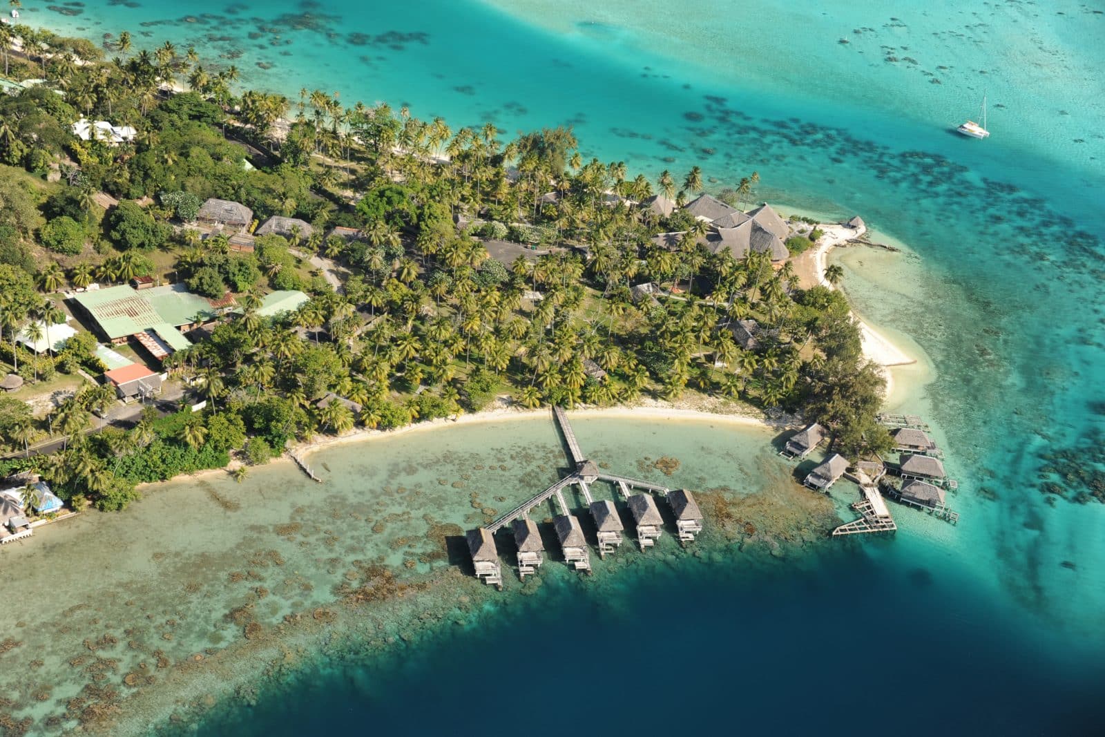 vue en hélicoptère de l'île de Bora Bora, avec l'eau turquoise et les hébergements sur pilotis